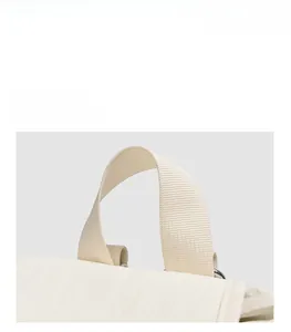 Vue rapprochée de la poignée en nylon beige et de l'anneau en D métallique du sac