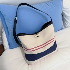 Close-up of navy striped canvas tote featuring an ivory toggle closure and leather strap