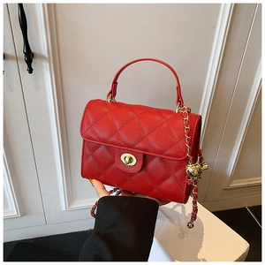 Detailed macro view of the red quilted leather bag with classic golden turn-lock closure