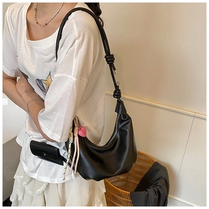 Detalle de bolso hobo negro de media luna con correa anudada y colgante de corazón
