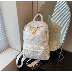 Detailed view of cream quilted backpack featuring adjustable straps and fluffy texture