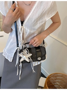 Sac bandoulière pailleté noir avec breloque étoile argentée porté par un mannequin