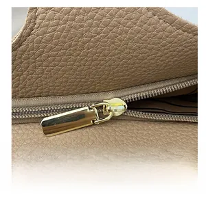 Detail of smooth gold metal zipper on premium brown lychee pattern leather tote bag