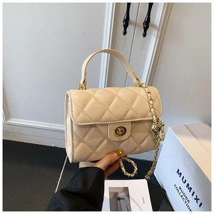 Detail of beige quilted bag featuring a golden ball adjustable chain and twist lock
