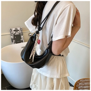 Detalle de bolso de media luna en cuero negro con pañuelo a rayas y colgante de corazón