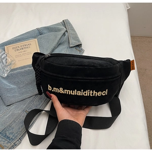 Détail du sac banane en toile noire avec broderie dorée et étiquette logo orange