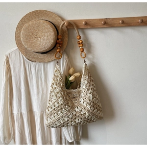 Detailed view of bohemian crochet tote with hollow patterns and wooden bead handle