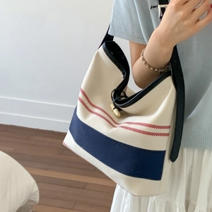 Detail of nautical striped canvas tote with black leather strap and horn buckle closure