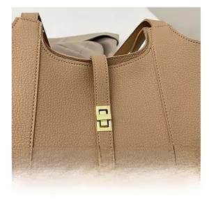 Detail of golden turn-lock closure on khaki pebble leather tote bag with precise stitching