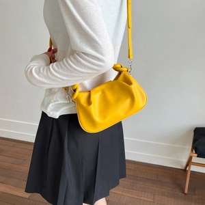 Detailed side view of bright yellow pleated cloud bag with adjustable shoulder strap