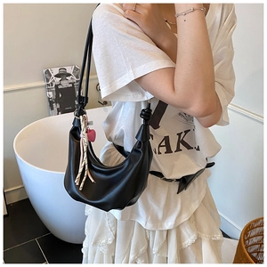 Detalle de bolso hobo negro con colgante de corazón rosa y decoración de cuerda trenzada