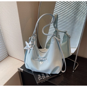 Close-up of light blue hobo bag with bow detail, heart pendant and star charms