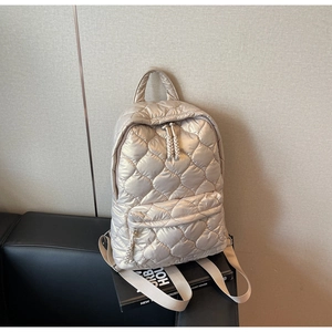 Detailed view of the heart-quilted pattern on the champagne nylon backpack surface