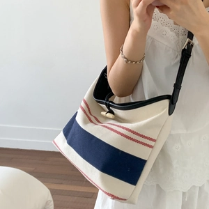 Close-up of canvas tote bag with blue stripes, faux leather straps and toggle closure