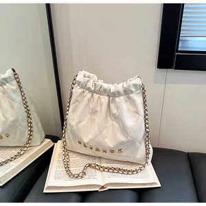 Detail of white quilted bucket bag featuring gold metal logo and leather chain strap