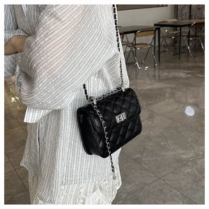 Detailed view of the quilted black shoulder bag featuring silver metal chain and twist lock