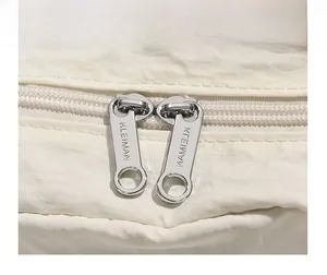 Détail macro des doubles fermetures éclair en métal argenté sur sac en nylon beige