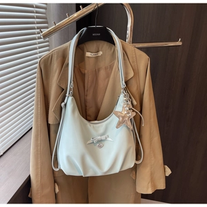 Detail of light blue hobo bag featuring bow decor and heart charm on a trench coat