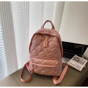 Detailed view of pink quilted nylon backpack with rhombus pattern and cord zipper pull