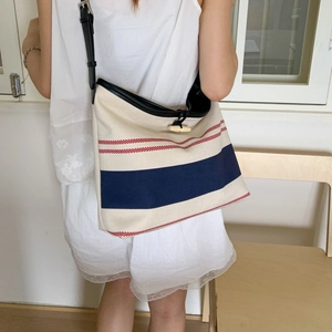 Detail of canvas striped tote bag featuring a leather trim and classic horn toggle closure