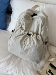 Minimalist beige nylon backpack with drawstring pocket and elegant pleated texture