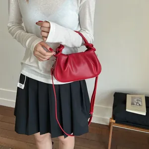 Detail of red ruched cloud bag with knotted handle and elegant faux leather texture
