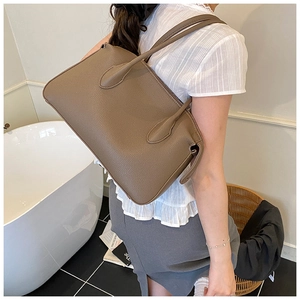 Borsa tote in pelle marrone con grana litchi indossata da una modella in casa