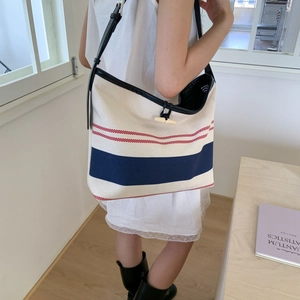 Close-up of striped canvas tote bag featuring a wooden horn button closure and leather strap