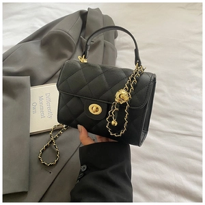 Close-up of quilted black leather handbag with gold metal lock and chain strap detail