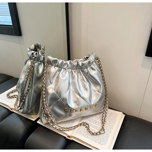 Detailed close-up of a silver quilted bucket bag with golden chain and metal logo