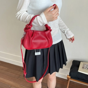 Detail of red ruched cloud bag showing leather texture and detachable strap on model