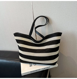 Detailed view of striped woven tote bag with durable black faux leather straps