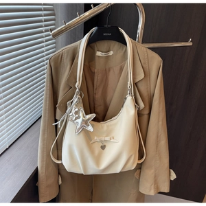 Detail of cream hobo bag with heart pendant, star charm and elegant ribbon bow