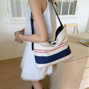 Detail of canvas tote bag with red and navy stripes and adjustable leather shoulder strap
