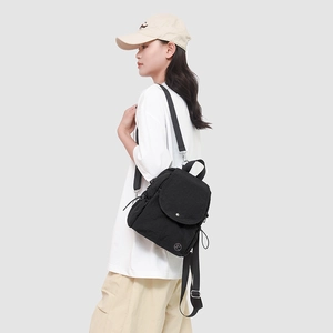 Détail d'un mini sac à dos en nylon noir porté par un modèle montrant sa taille et ses bretelles