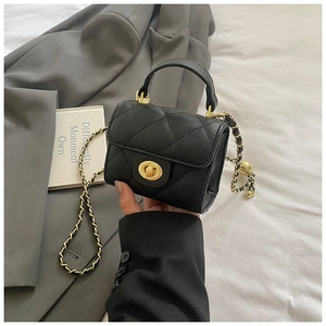 Detail of black quilted mini bag with lychee texture and gold metal turn-lock closure