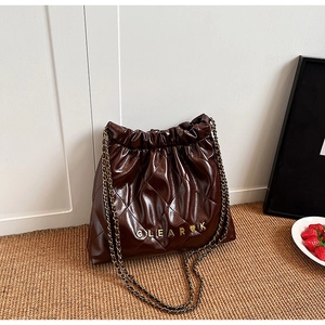 Detail of dark brown quilted drawstring bucket bag with shiny faux leather and gold chain