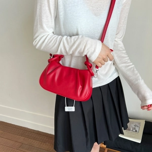Detail of red ruched cloud bag with knotted handles and silver metal strap hooks