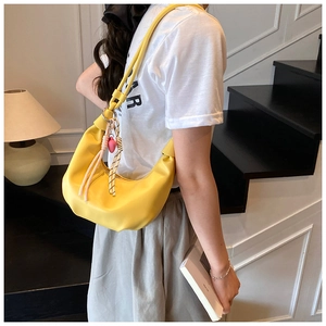 Detalle de bolso hobo amarillo de media luna con colgante de corazón en modelo