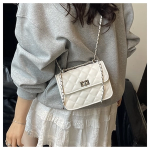 Close-up of white quilted leather crossbody bag with metal chain strap on model