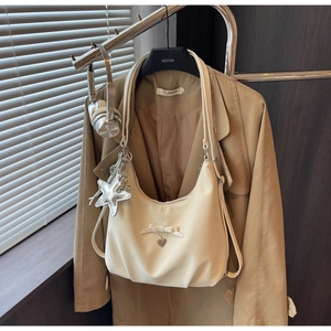 Detail of off-white hobo bag featuring bow decor and silver star pendant on a hanger