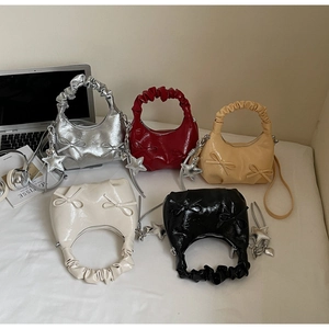 Flat lay of small pleated bow shoulder bags in five colors with star charms