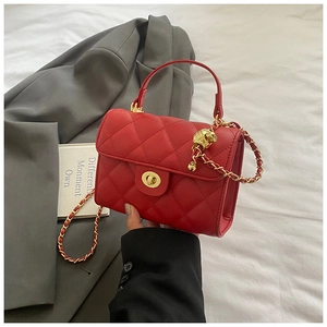 Close-up of red quilted leather mini bag with gold chain strap and metal ball adjuster