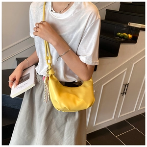 Detalle del bolso de media luna amarillo brillante con cuero mate y correa anudada