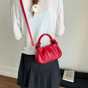 Detailed close-up of a red pleated cloud bag with silver hardware on a female model
