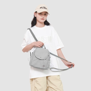 Gros plan d'un mini sac à dos en nylon gris imperméable avec cordons décoratifs