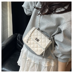 Close-up of white quilted crossbody bag with silver twist lock and metal chain strap