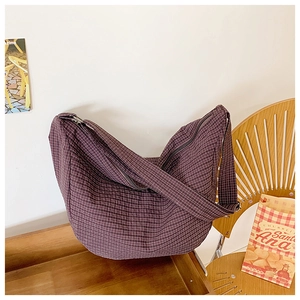 Detailansicht der dunkelvioletten karierten Nylon-Umhängetasche auf einem Holztablett