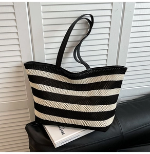 Detail of black and white striped knit tote bag with slender leather shoulder straps