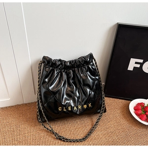 Close-up of black quilted leather bucket bag with gold chain strap and metal logo